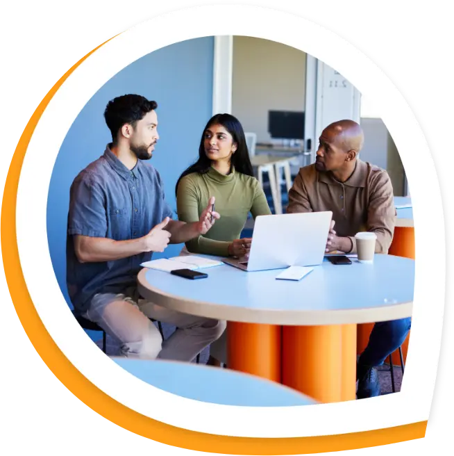 Coworkers gather around a table looking at a laptop